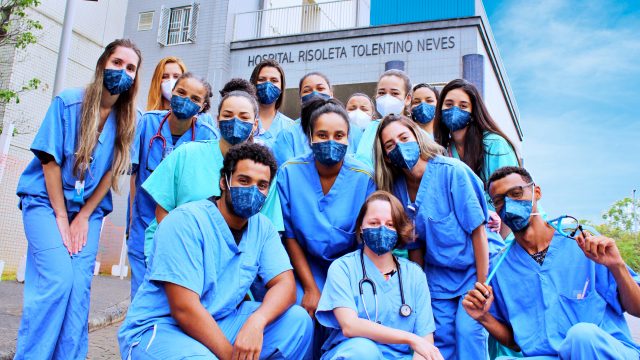 Um grupo de médicos usando máscara na frente do Hospital Risoleta Tolentino Neves